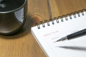 reviewing completed and unfinished tasks in a weekly planner
